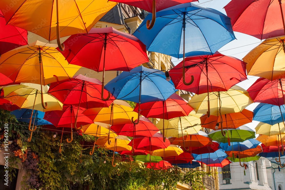 Bright and colorful umbrellas decorate a restaurant. The house covered with wild grapes in Kyiv, Ukraine.