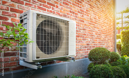 Air conditioning heat pump outdoor unit against brick wall. photo