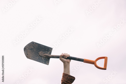 Fototapete A man's hand holds a bayonet shovel on a white background