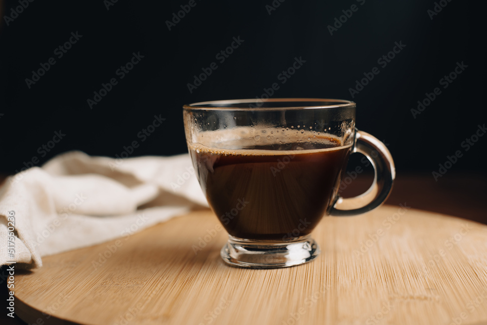 Taza de café, desayuno, taza de vidrio encima de bandeja de madera, en mesa de café de madera, con fondo oscuro, fondo negro, close-up Taza de café, desayuno, taza de vidrio encima de bandeja de madera, en mesa de café de madera, con fondo oscuro, fondo negro, close-up