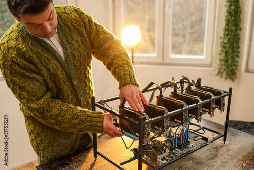 Man adjusting computer graphics in cryptocurrency mining rig