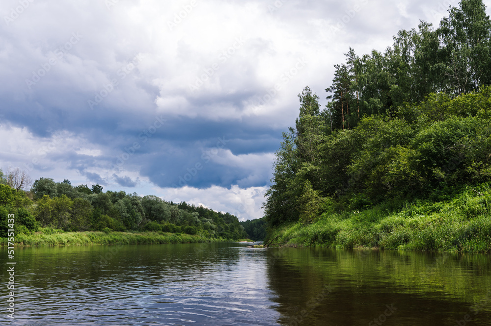 Scenic landscape of river Gauja at cloudy day. Stormy sky. Summer nature. Green trees. Reflection in water. Scenic landscape of river Gauja at cloudy day. Stormy sky. Summer nature. Green trees. Reflection in water.
