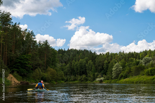 Canoeing on Gauja river at cloudy day. Stormy sky. Pines on shore. Two people in boat. © Anastasia
