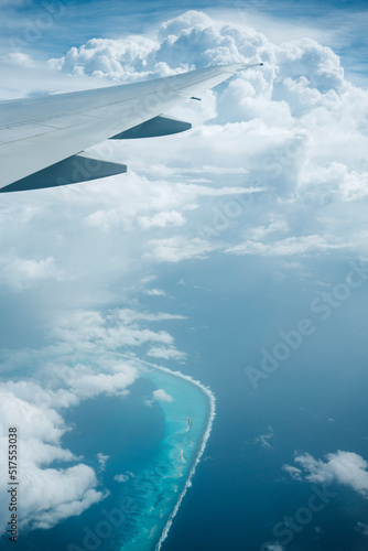 Maldivian atoll passes beneath commercial aeroplane on a bright but storm day - Portrait 