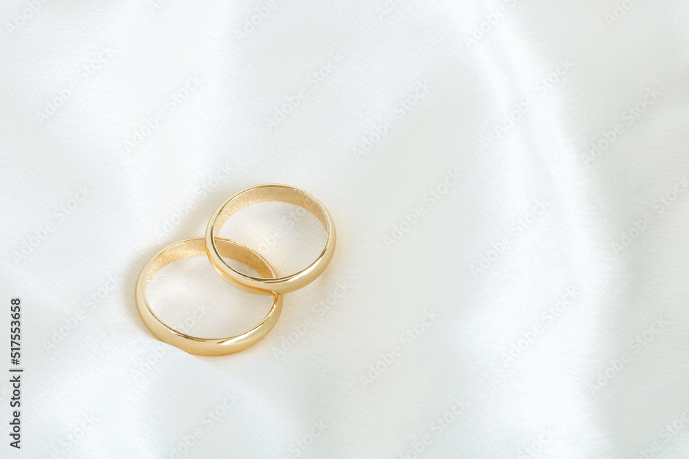 Two gold wedding rings on a white satin. Two gold wedding rings on a white satin.