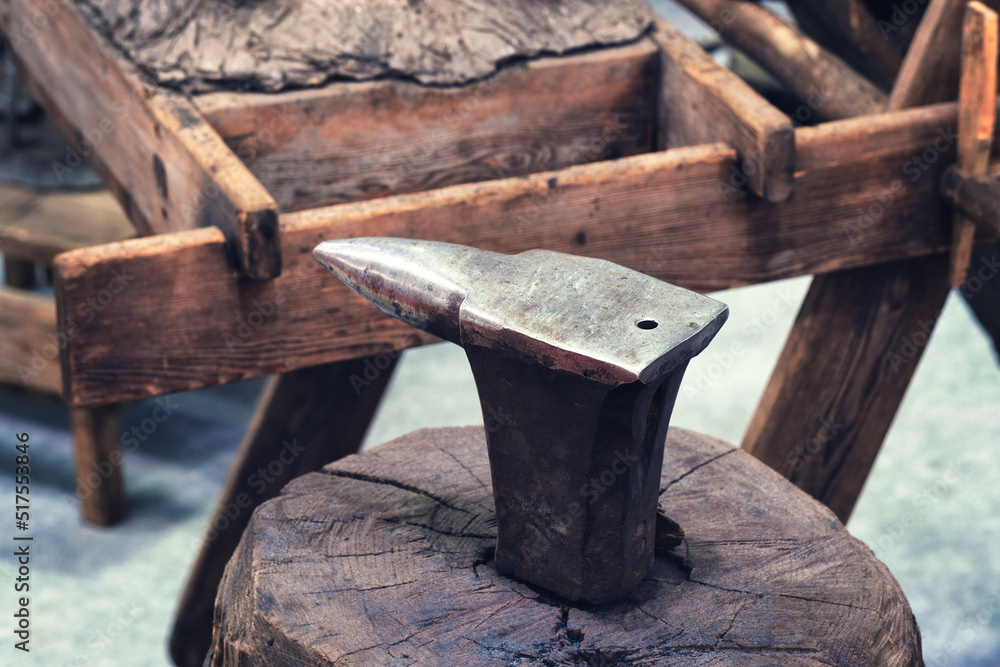 Anvil on a wooden stump in a forge in a rustic old style Anvil on a wooden stump in a forge in a rustic old style