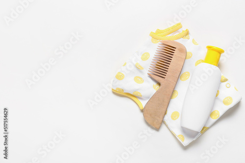 Baby bodysuit  wooden hair comb and bottle with cosmetic product on white background