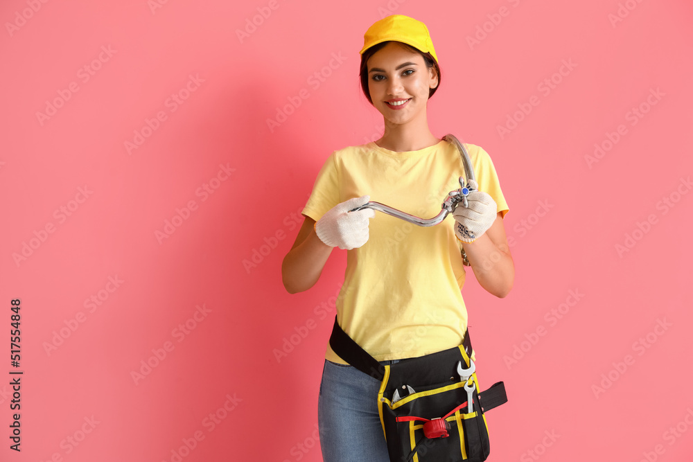 Female plumber with faucet on pink background Female plumber with faucet on pink background