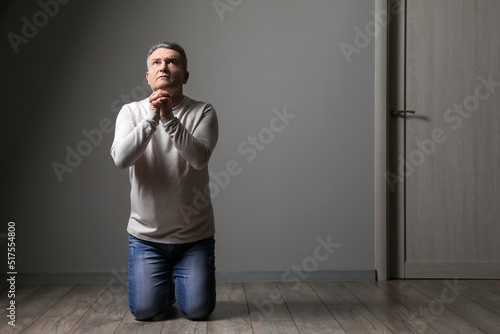Praying mature man in dark room
