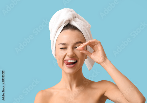 Pretty young woman with small makeup sponge on blue background