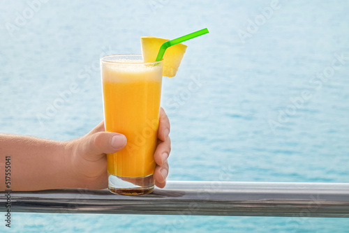 Male hand with glass of fresh tropical cocktail at sea resort