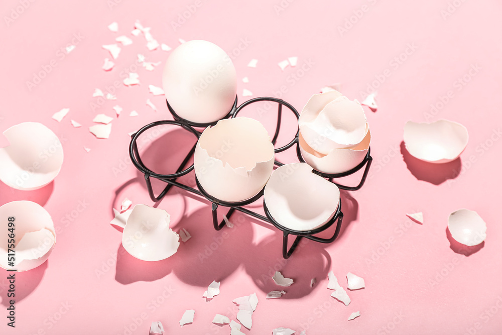 Holder with broken egg shells on color background