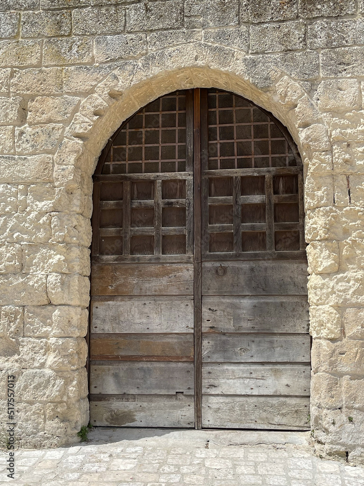 Brown wooden door surrounded by stone arch on side of ancient stone building