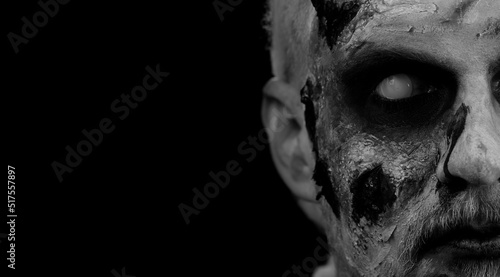 Obraz na plátně Close-up face of sinister man with horrible scary Halloween zombie makeup making faces, looking ominous at camera, trying to scare