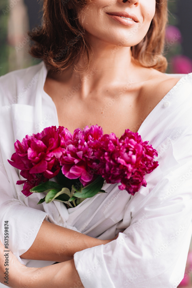a gentle beautiful middle-aged woman in white clothes with a bouquet of peonies. a gentle beautiful middle-aged woman in white clothes with a bouquet of peonies.