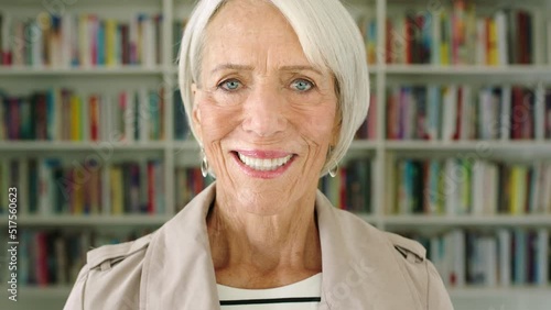 Face portrait of happy senior woman with library. Smart, wise and enlightened mature female. Big collection of books in home office for a teacher or professor. Knowledgable on various topics