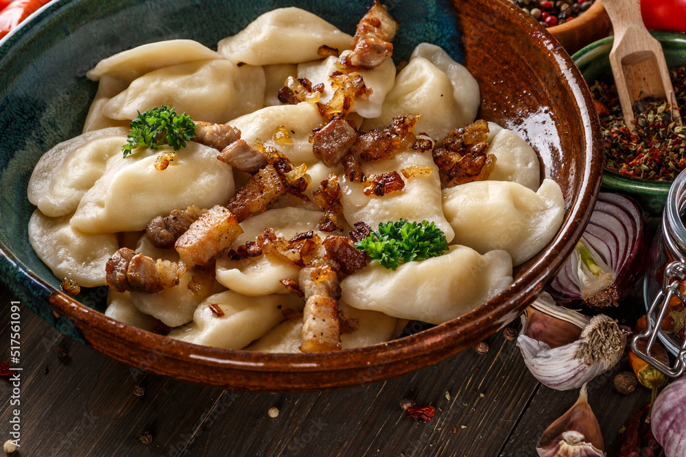 Pierogi or pyrohy, varenyky, vareniki, dumplings served with caramelized salted onion in bowl on wooden table - traditional Ukrainian food