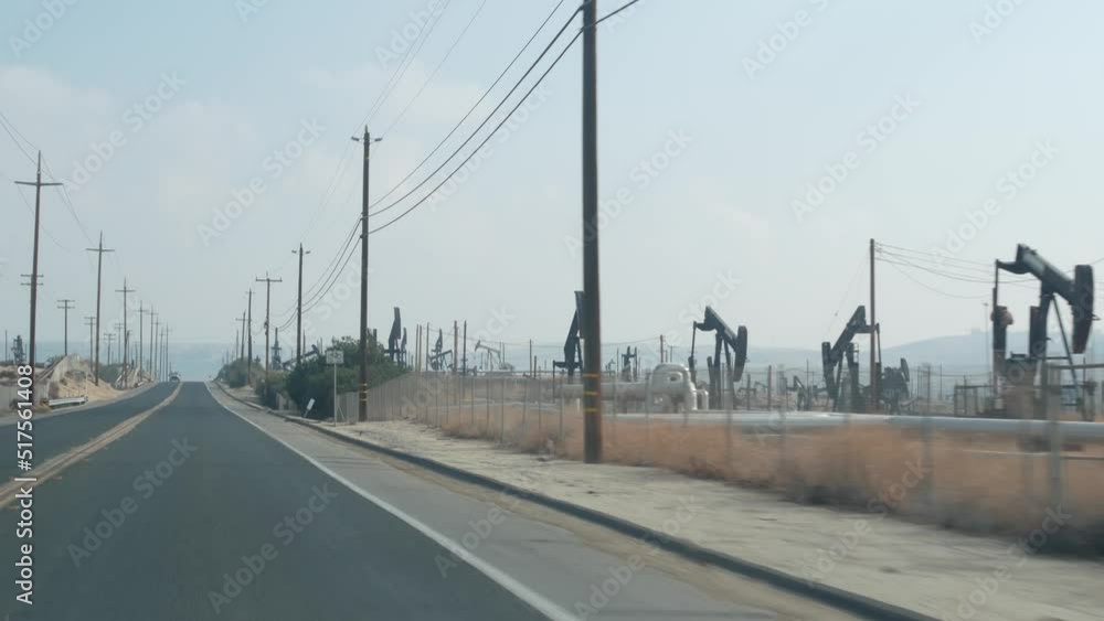 Wells with pump jacks on oil field, California USA. Rigs for crude fossil extraction working on oilfield. Industrial landscape, derricks in desert valley. Many pumpjacks platforms on oilwells pumping. Wells with pump jacks on oil field, California USA. Rigs for crude fossil extraction working on oilfield. Industrial landscape, derricks in desert valley. Many pumpjacks platforms on oilwells pumping.