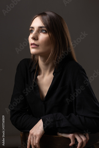 Portrait of a young brunette with long hair in the studio. Dramatic photo in dark colors.