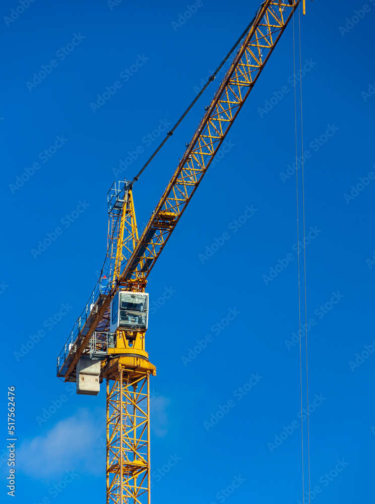 Tower crane with an arrow and cabin on blue sky background. Tower crane with an arrow and cabin on blue sky background.