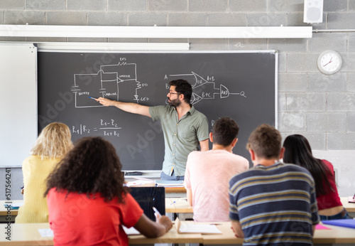 Young male teacher giving a science class explaining at the blackboard in a high school. Back to school. High school, education photo