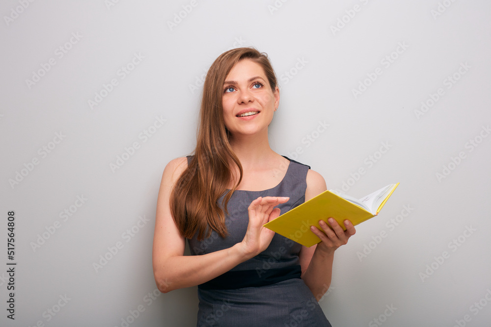 Happy smiling business woman in dress with open yellow book thinking and looking up. isolated female business person portrait. Happy smiling business woman in dress with open yellow book thinking and looking up. isolated female business person portrait.