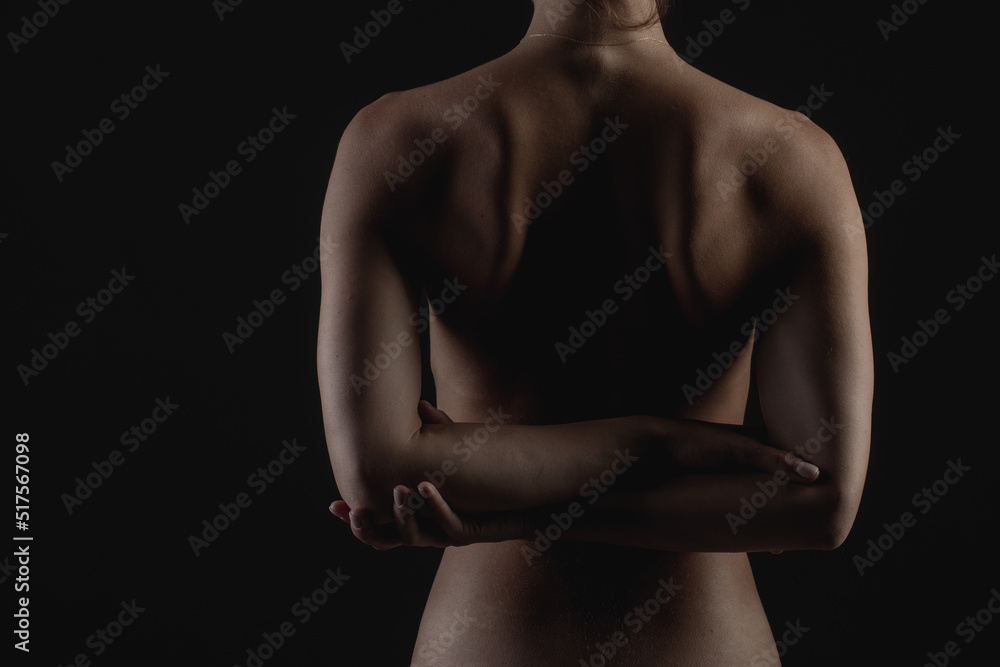 Naklejka premium girl's back close-up on a dark background, the concept of treatment of the spine and back