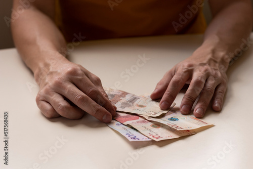 Man's hands on a table, counting Colombian bills