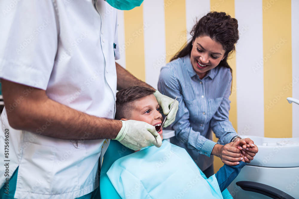 Cute little boy sitting on dental chair and having dental treatment. His mother is with him. Cute little boy sitting on dental chair and having dental treatment. His mother is with him.