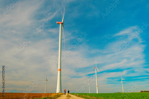 Windmills and People near on the road on a blue sky background.Wind generators.Natural energy.Alternative energy sources.Environmentally friendly natural energy source. 