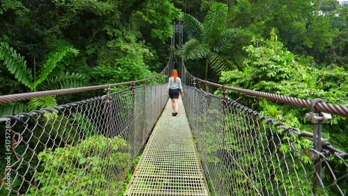 Slow-motion moves forward shot, a woman walking the hanging bridge of La Fortuna in the middle of the rain forest in Costa Rica. photo