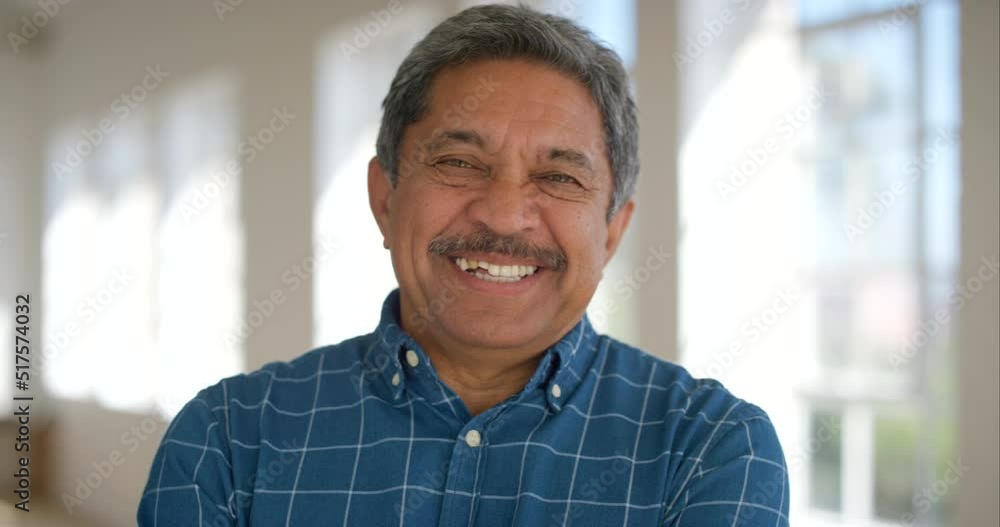 Portrait of a happy retired male looking cheerful standing inside a bright room. Face of a laughing mature latino man standing in an empty office or home. Smiling confident senior enjoying retirement Portrait of a happy retired male looking cheerful standing inside a bright room. Face of a laughing mature latino man standing in an empty office or home. Smiling confident senior enjoying retirement