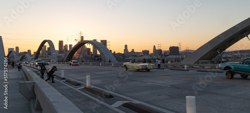 Low-rider cars crossing over the 6th Street Bridge in Los Angeles with the skyline in the distance