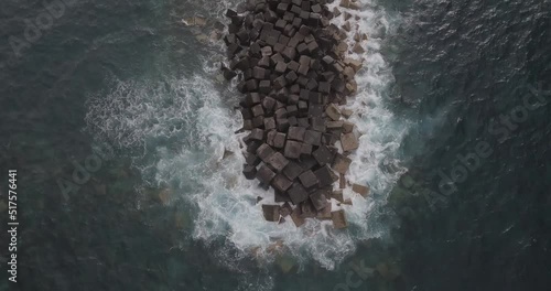 waves crashing over a spit of rocks in the sea. shot on a mavic pro in D-log at 4K photo