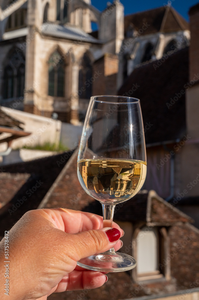 Tasting of white grand cru classe chablis wine with old French houses on background, Burgundy, France