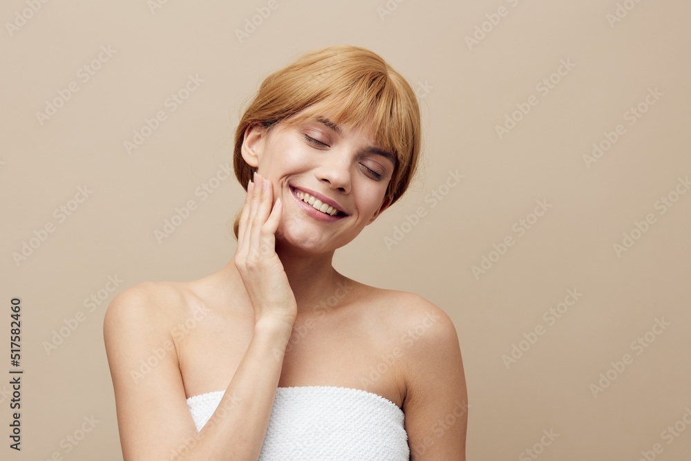 a pleasant, relaxed, attractive woman stands on a beige background and closes her eyes with pleasure and touches her face with her hand a pleasant, relaxed, attractive woman stands on a beige background and closes her eyes with pleasure and touches her face with her hand