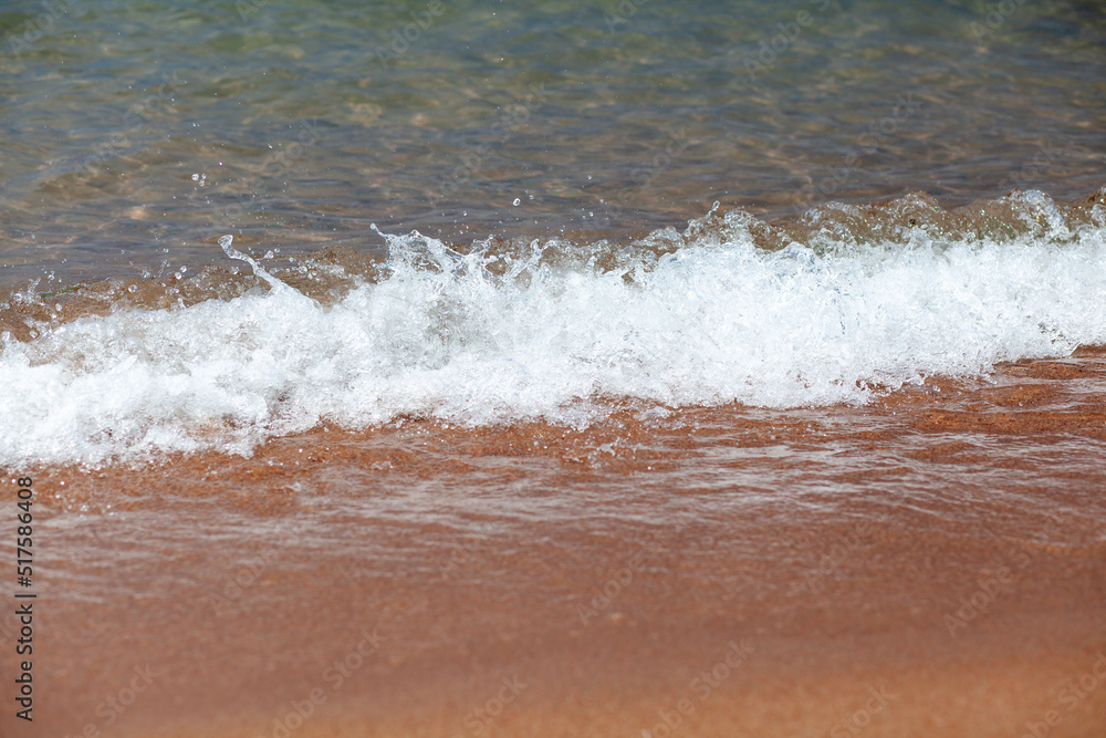 A soft wave runs on a sandy shore on a summer day. Empty space can be used as background for display or montage your top view products. A soft wave runs on a sandy shore on a summer day. Empty space can be used as background for display or montage your top view products.