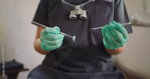 Closeup hands of dentist holding tools for teeth exam or cleaning. Oral hygienist or health care worker with mouth mirror and excavator in her hands, sitting in a dental clinic or medical surgery. photo