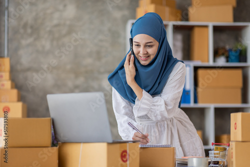 Photography Muslim young Asian woman working at home doing sme ecommerce online small business entrepreneur checking postal parcels to delivery to online customers, startup Muslim Sme business concept