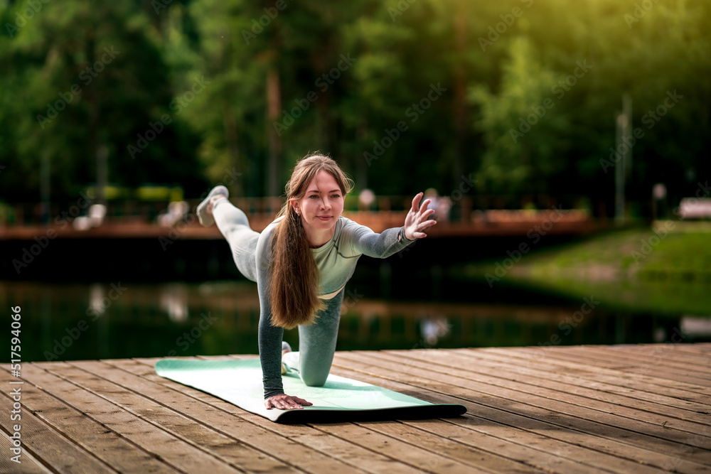 Beautiful woman practicing Yoga by the lake - Toned image
