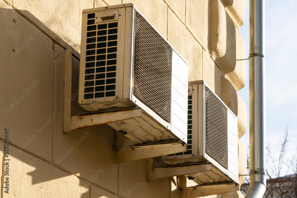 Fototapeta premium two units of outdoor air conditioners for heat dissipation are hung on the wall outside the building