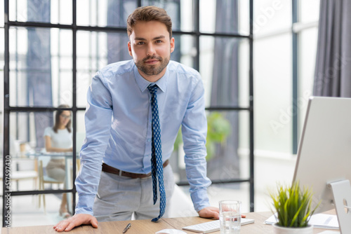 Young modern business man analyzing data using computer while working in the office with collegues on the background.