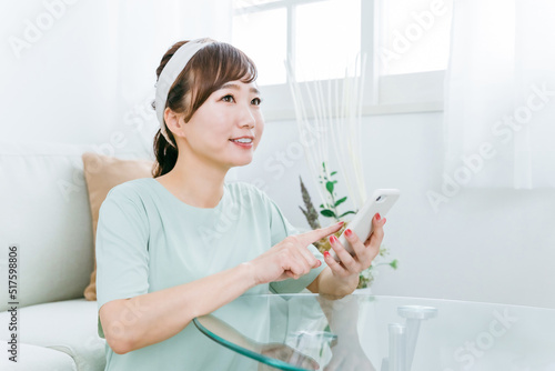 家でスマホを使う笑顔の日本人女性（アプリ）
