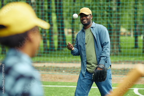 Photography African happy father throwing ball to his son during their baseball game outdoor