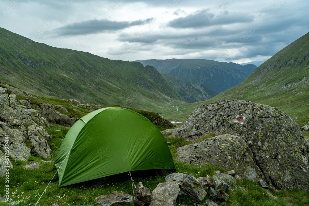 green tent in rocks with view on mountain valley