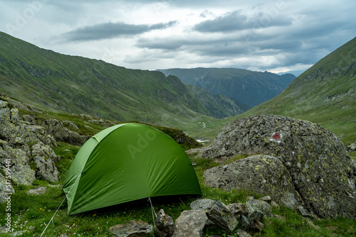 green tent in rocks with view on mountain valley