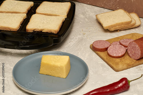 sandwich maker cheese sausage and bread on the table