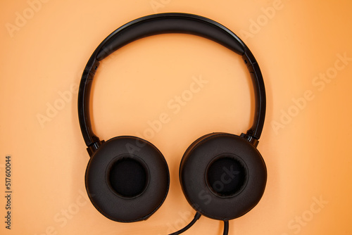 Modern Black Headphones isolated on orange background. Top view.