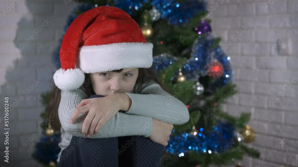Punished child at Christmas. A little sad punished child sits on the floor against Christmas tree. Punished child at Christmas. A little sad punished child sits on the floor against Christmas tree.