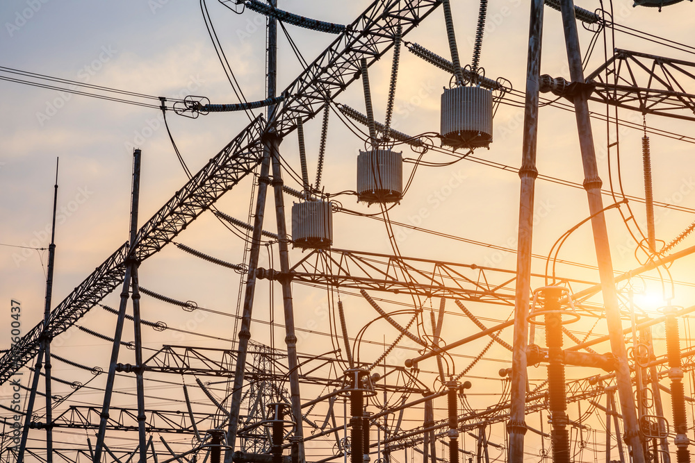 High voltage power tower in substation. Transmission power line. Electricity pylons and sky clouds background at sunset.